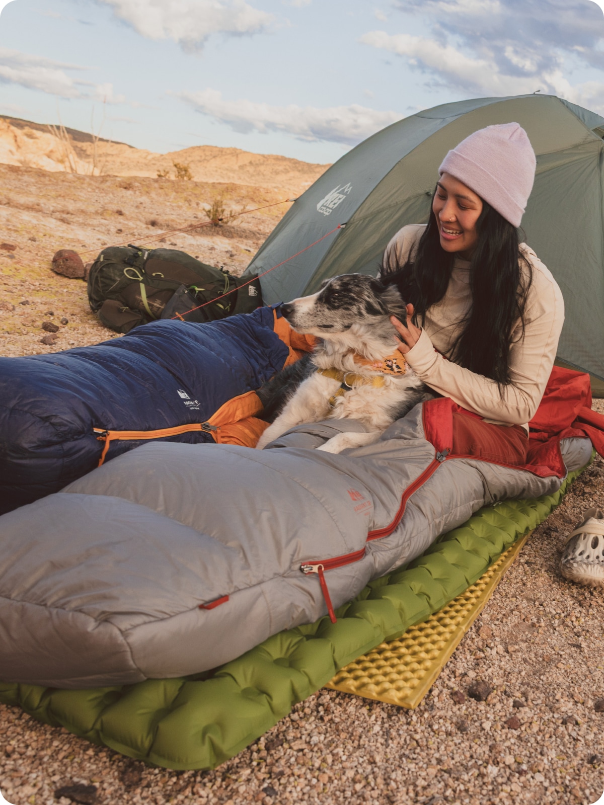 A person relaxes inside of a sleeping bag with a very good pup.