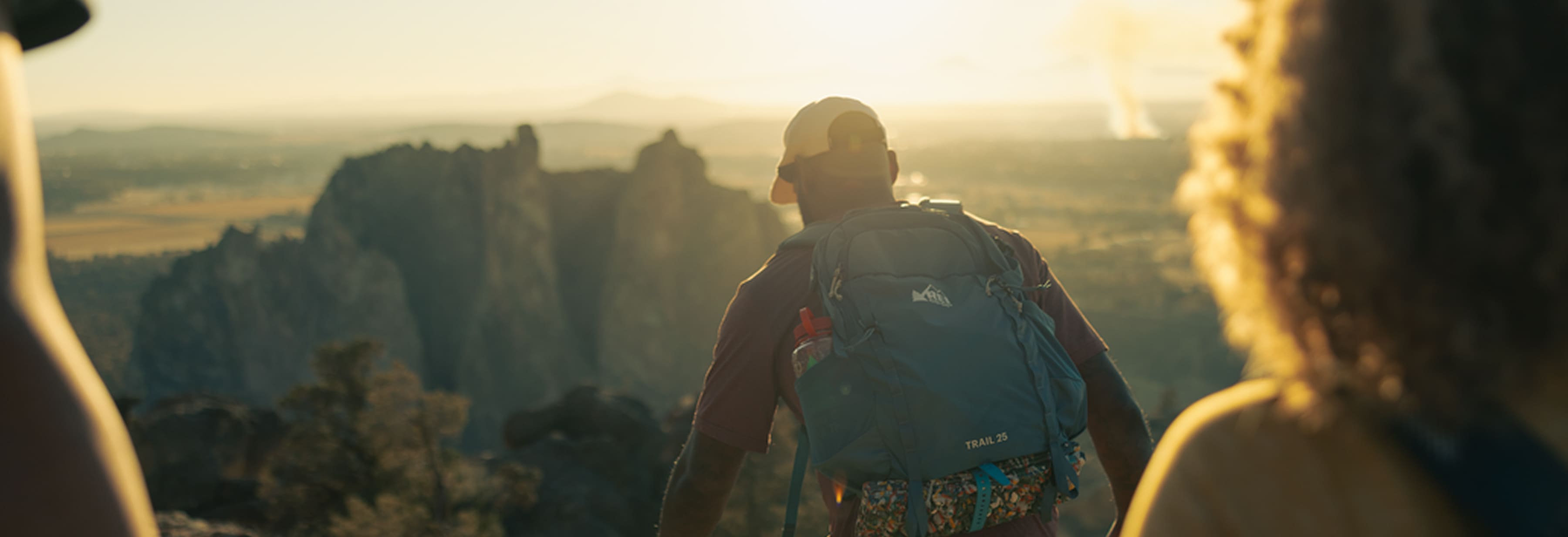 Three people hike while the sun begins to set.