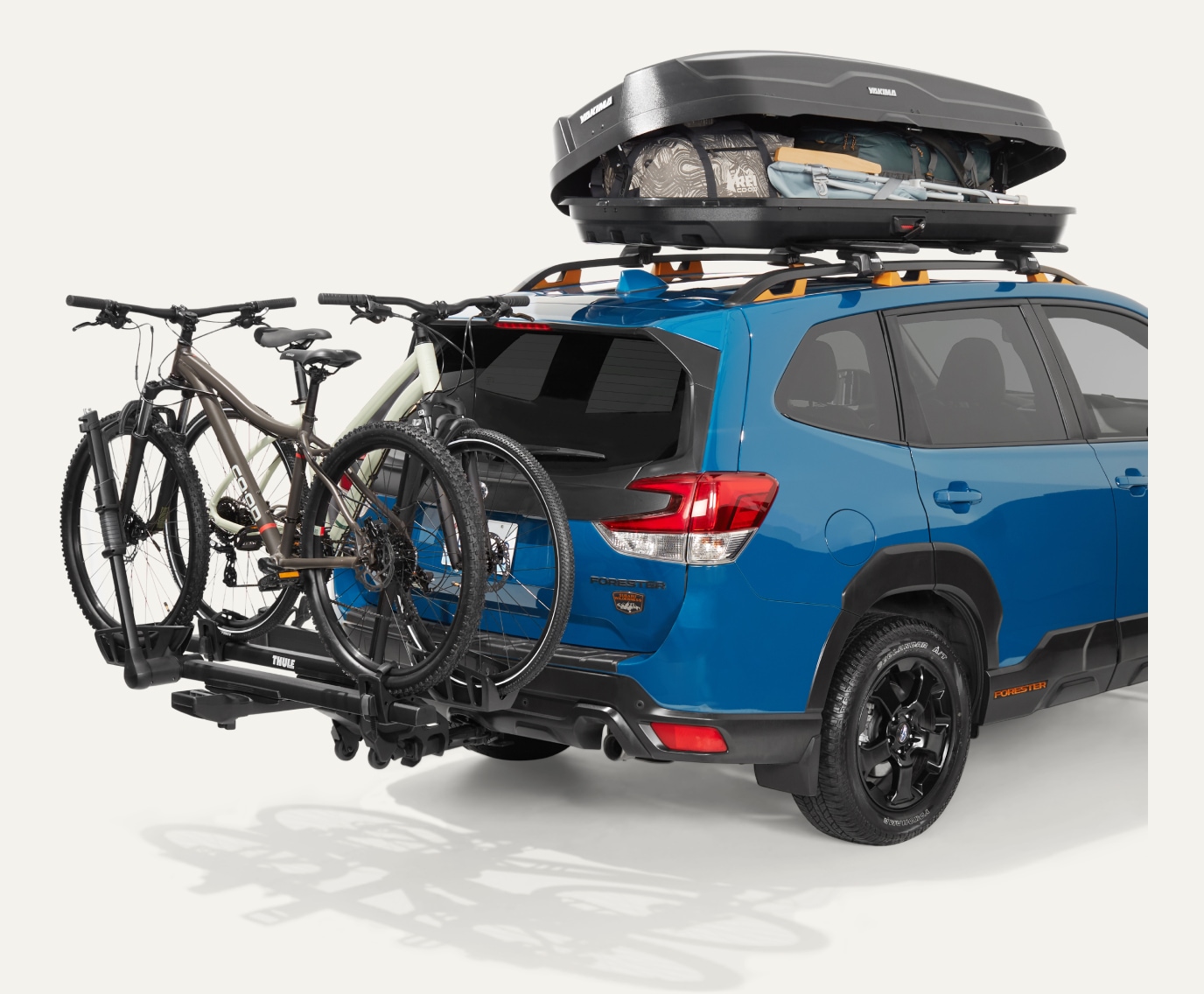 A blue Subaru Forester with a Yakima roof box & a Thule bike rack.