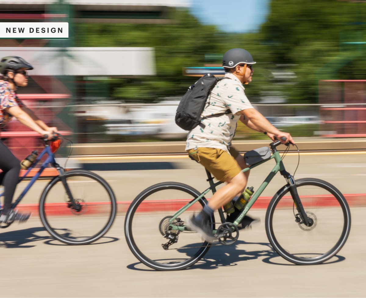 Two people on bikes speed through a paved road.