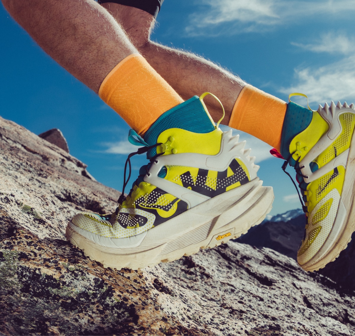 A person climbs rocks in their HOKA Mafate X Hike shoes.