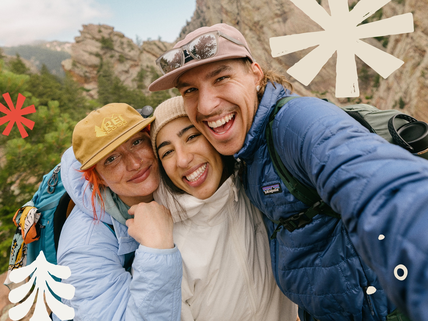 Three people smile and hug while taking a group photo.