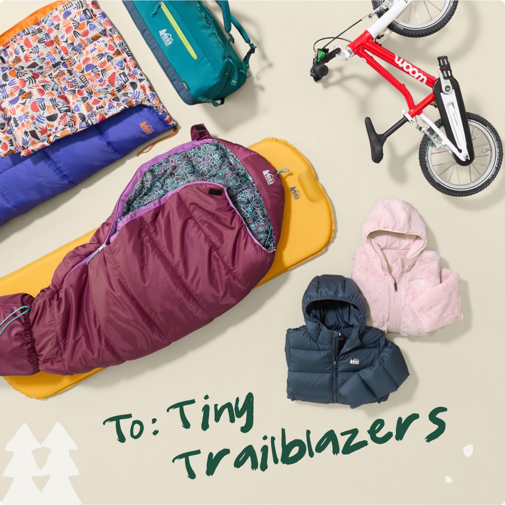 To: Tiny trailblazers. A collage of kids’ clothing, a bike, sleeping bags & pads, and a bag.