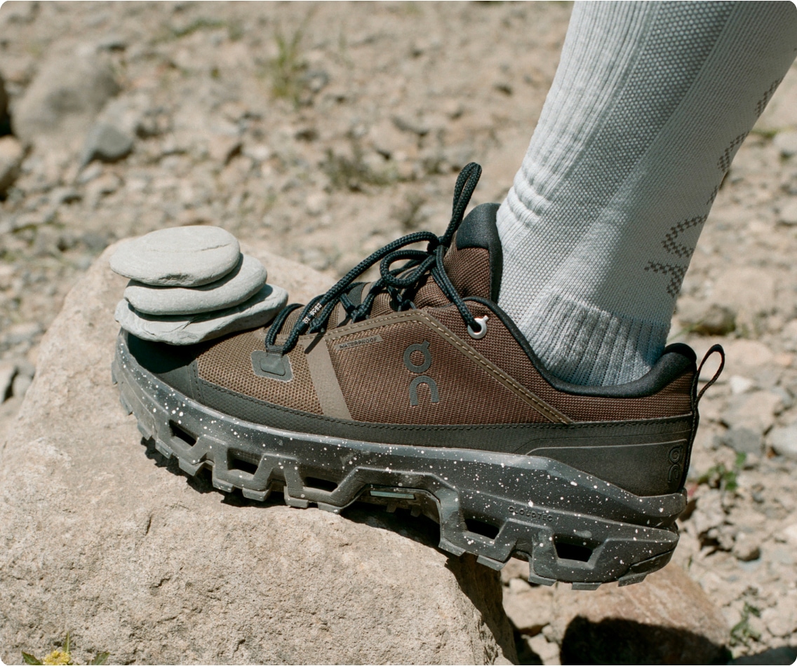 Stack of 3 rocks balancing on the tip of a brown shoe.