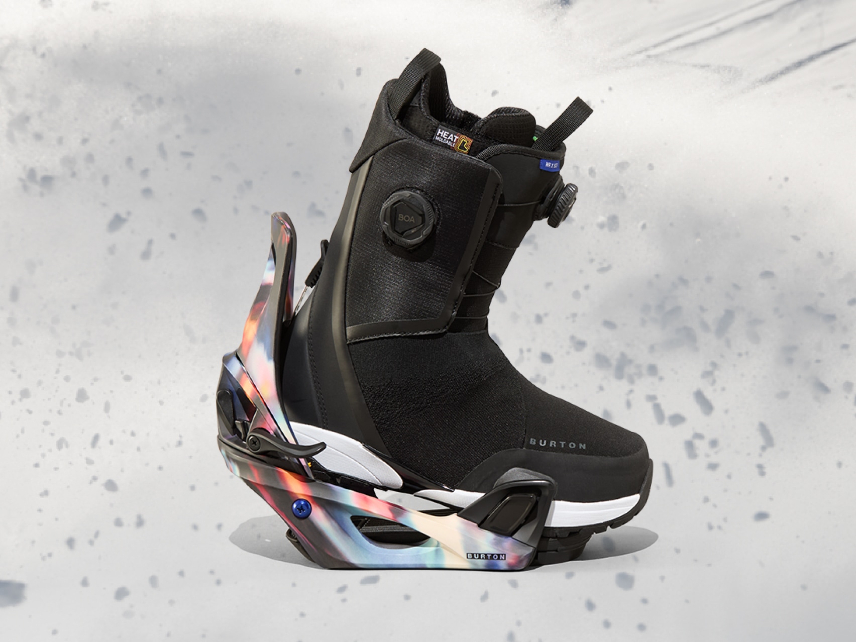 A snowboard boot and binding on a snowy background.