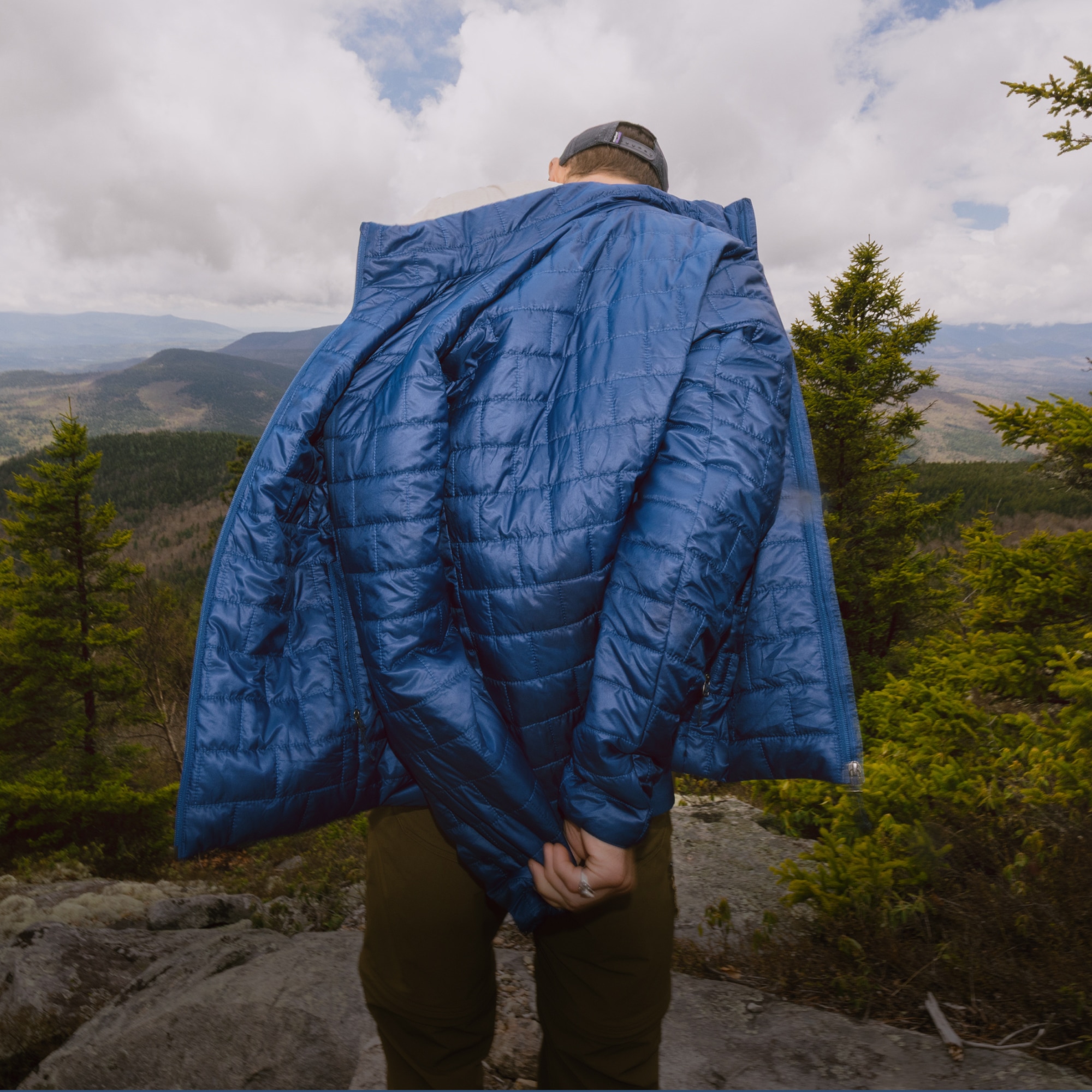 A hiker stops to take off their Patagonia Nano Puff jacket.