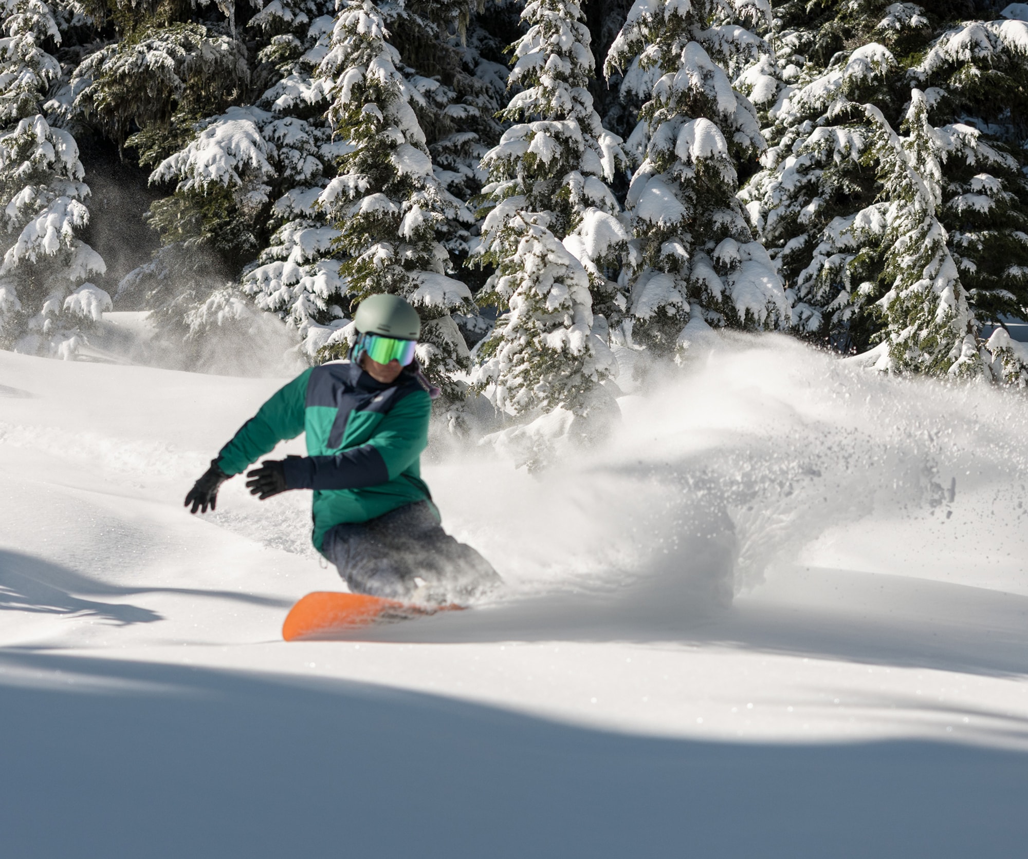A snowboarder carves down a snowy mountain.