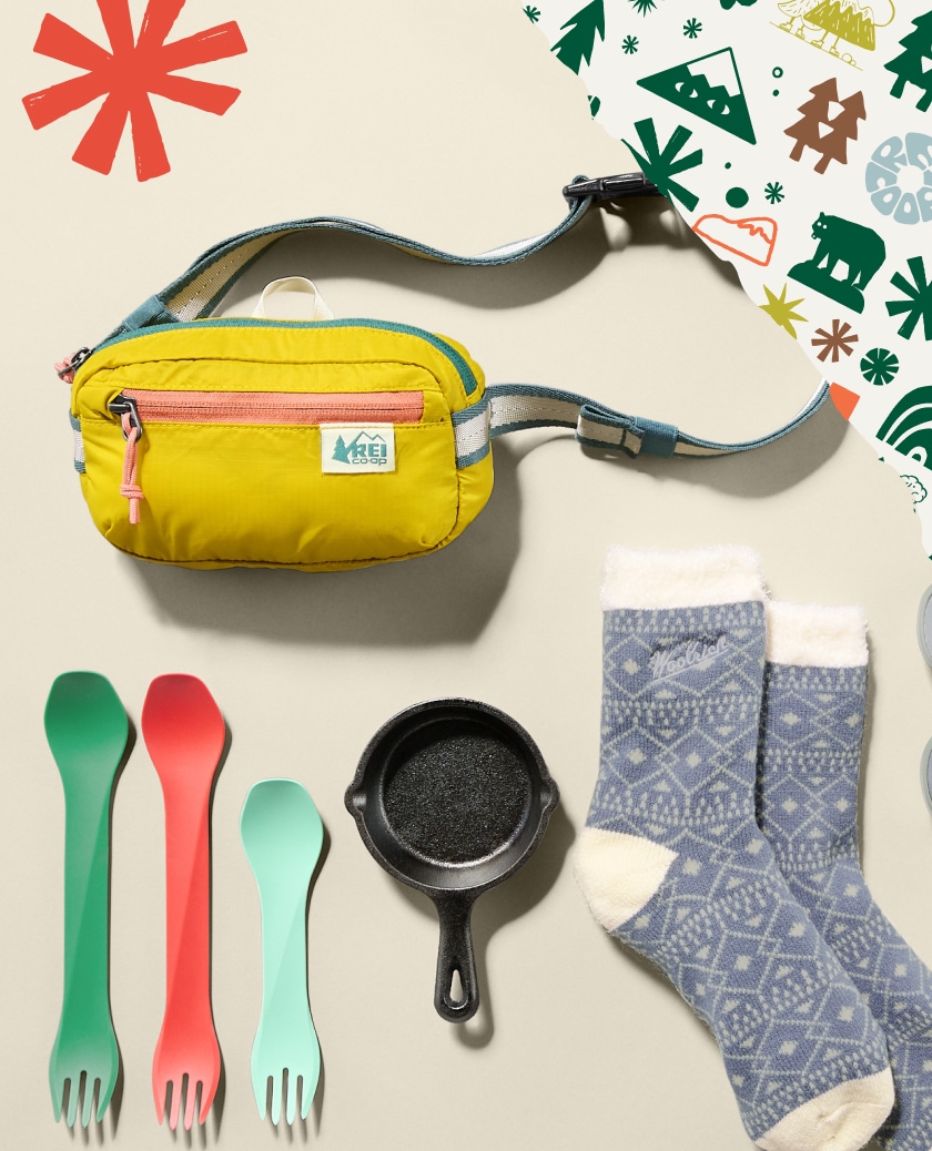 Wrapping paper with holiday motifs and a collage of stocking stuffers including a pan, a pair of socks, utensils, and a bag.