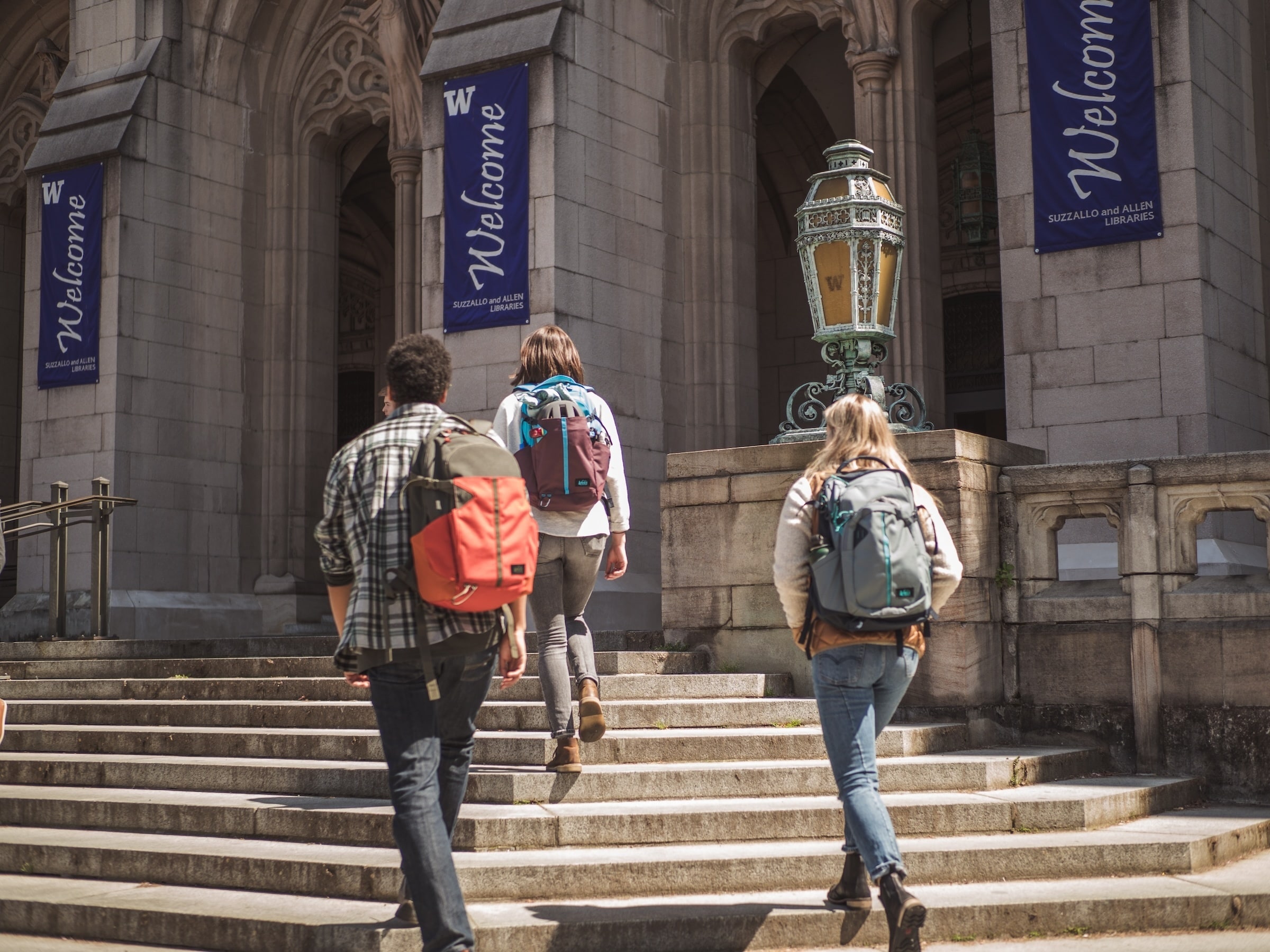 Three people walk up a set of stairs before going into a campus library.