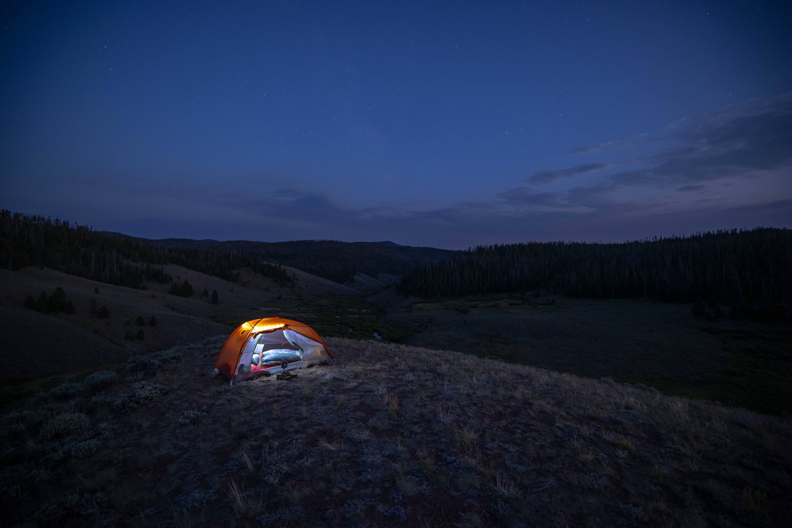 Landscape shot with a Big Agnes Copper Spur mtnGLO 2 Tent in the foreground. The tent has an orange rainfly.