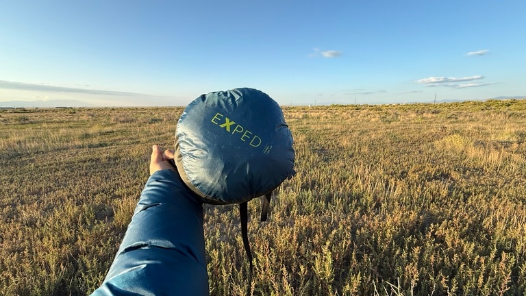 Picture of an arm holding out the Exped Terra 15 packed in its stuff sack.