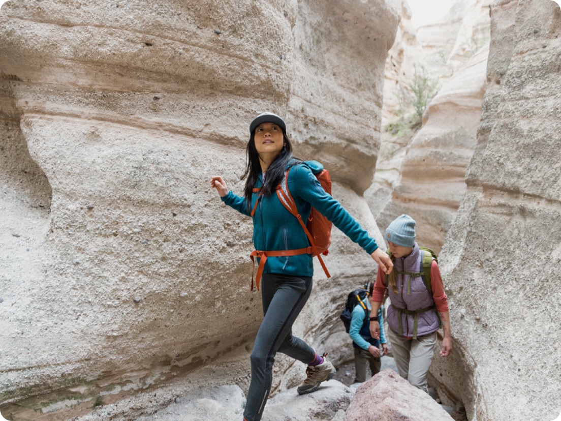 Three people hike a rocky path through a canyon.