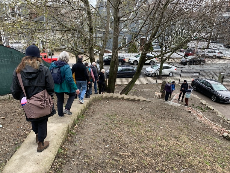 A group of people descent an urban staircase in a single-file line.