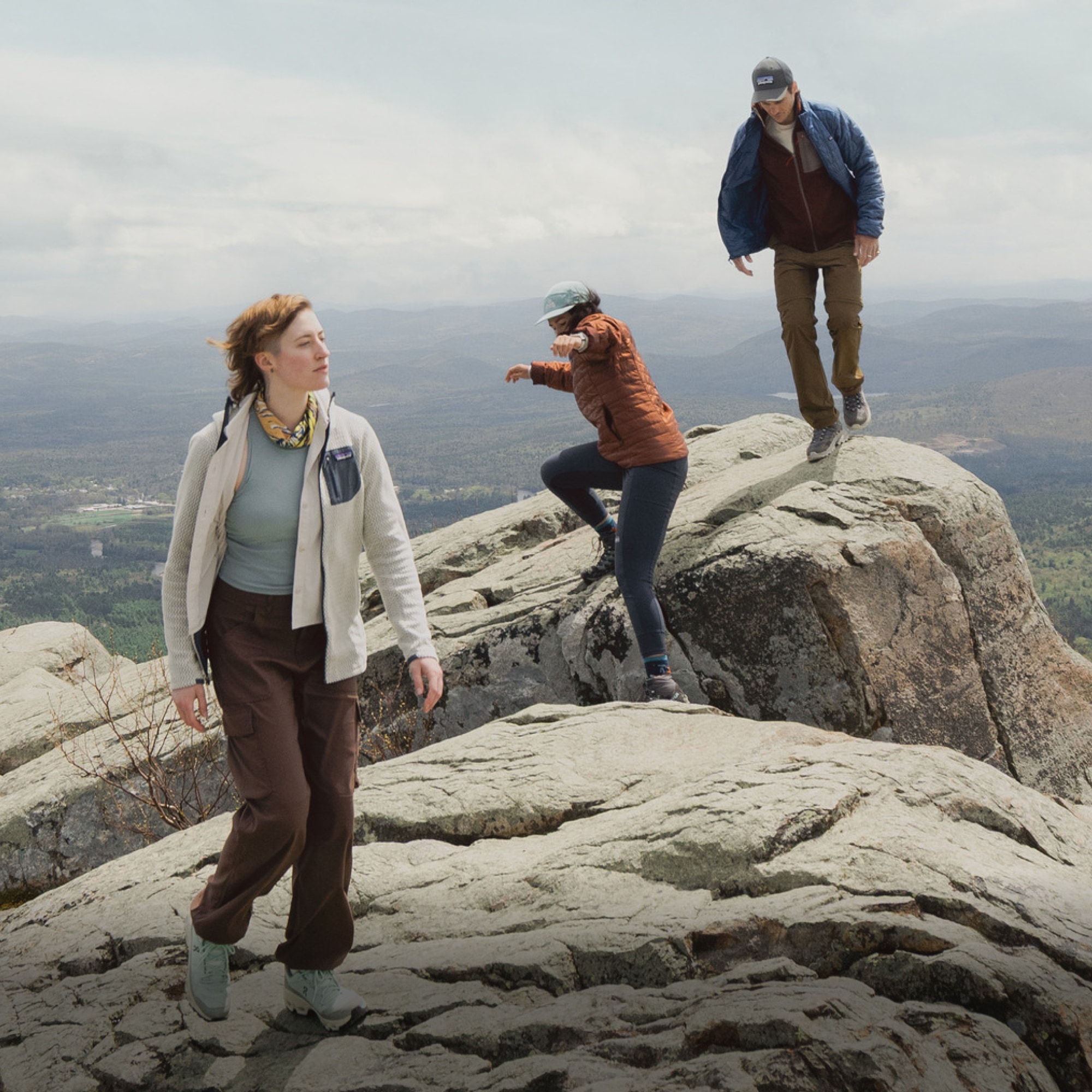 A group of people hike over large rocks on a sunny day.