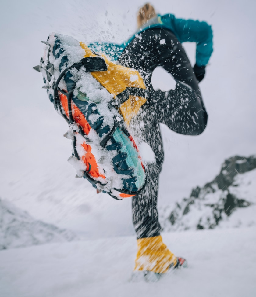 A person runs through the snow with the Kahtoola MICROspikes Ghost traction system on their shoes.