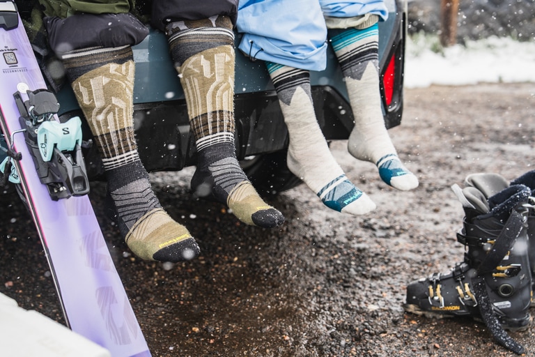 A photo of two people's legs, with knee high ski socks.