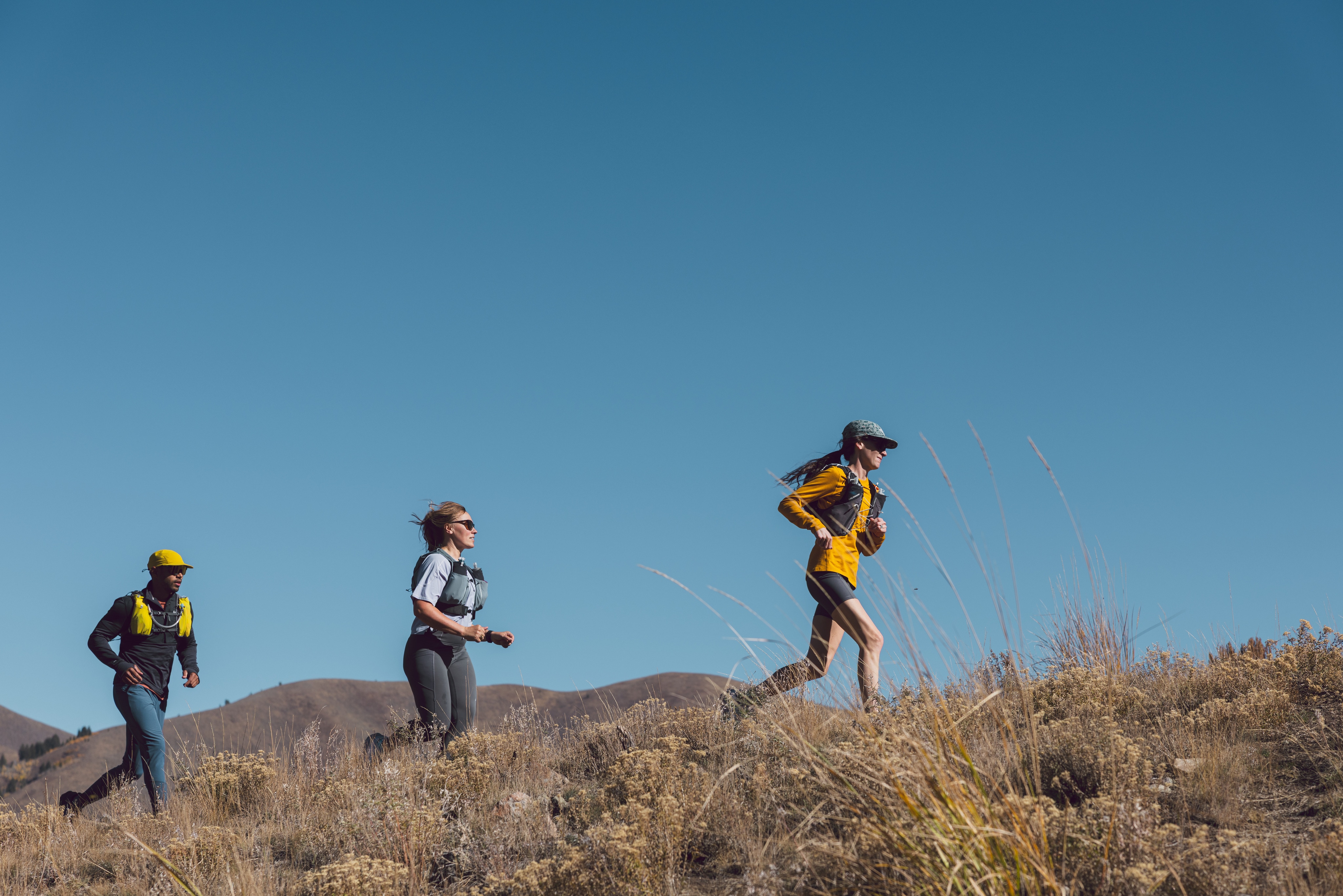 Three people run on a trail