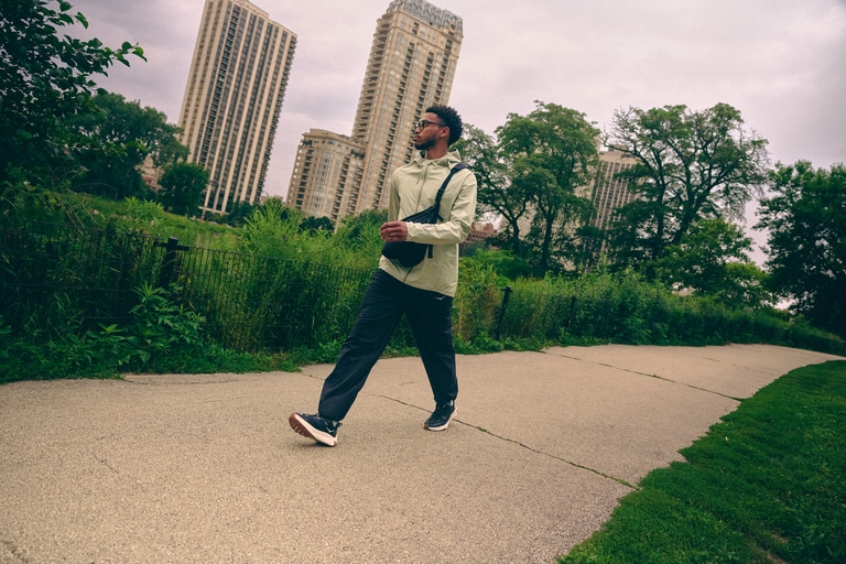 A person walks down a sidewalk in an urban setting