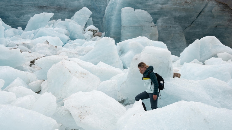 A woman walks through a glacier field.