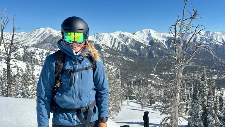 A skier in front of a wintery landscaping wearing Smith goggles.
