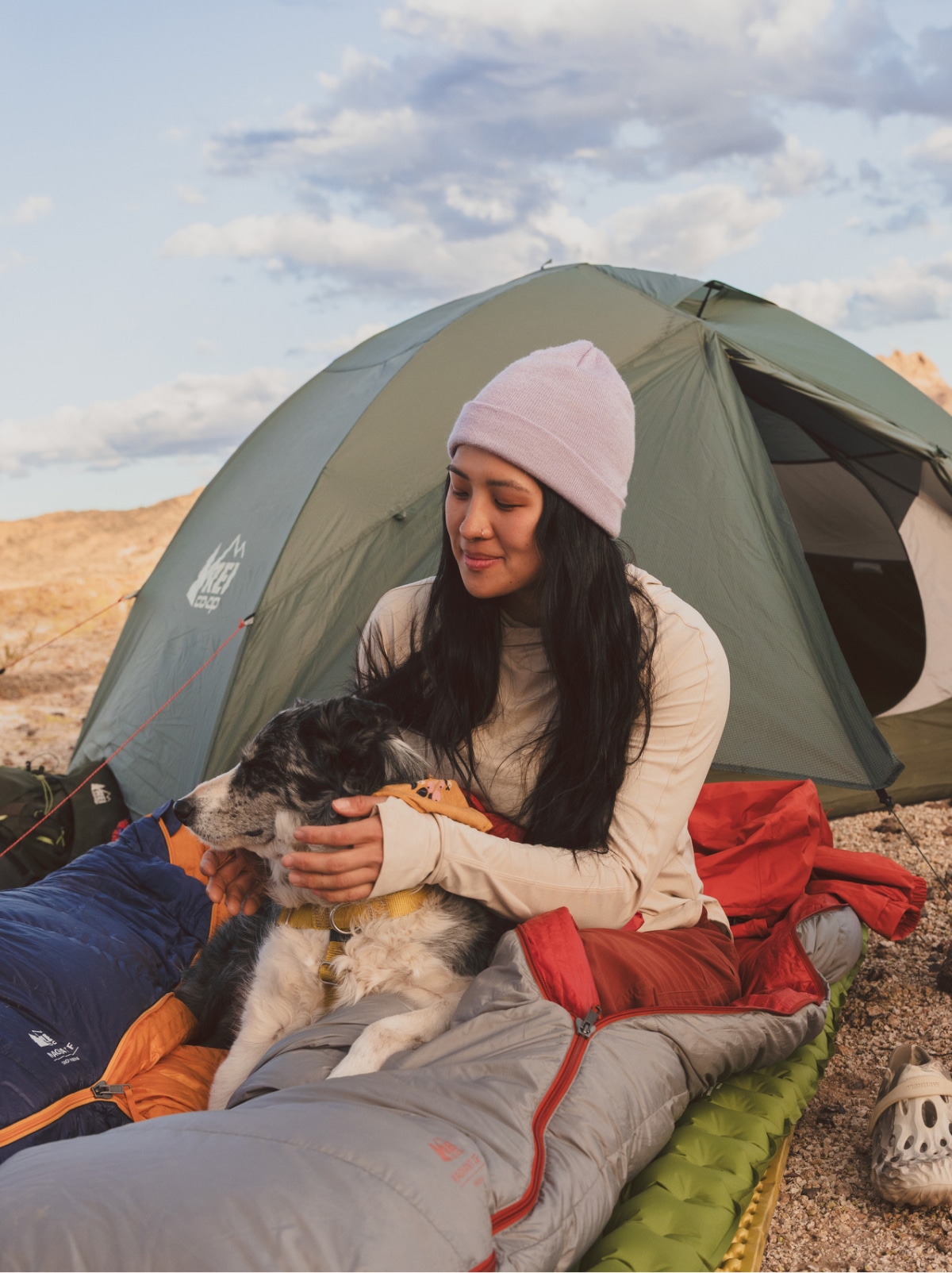 A person relaxes in a sleeping bag with a very good pup.