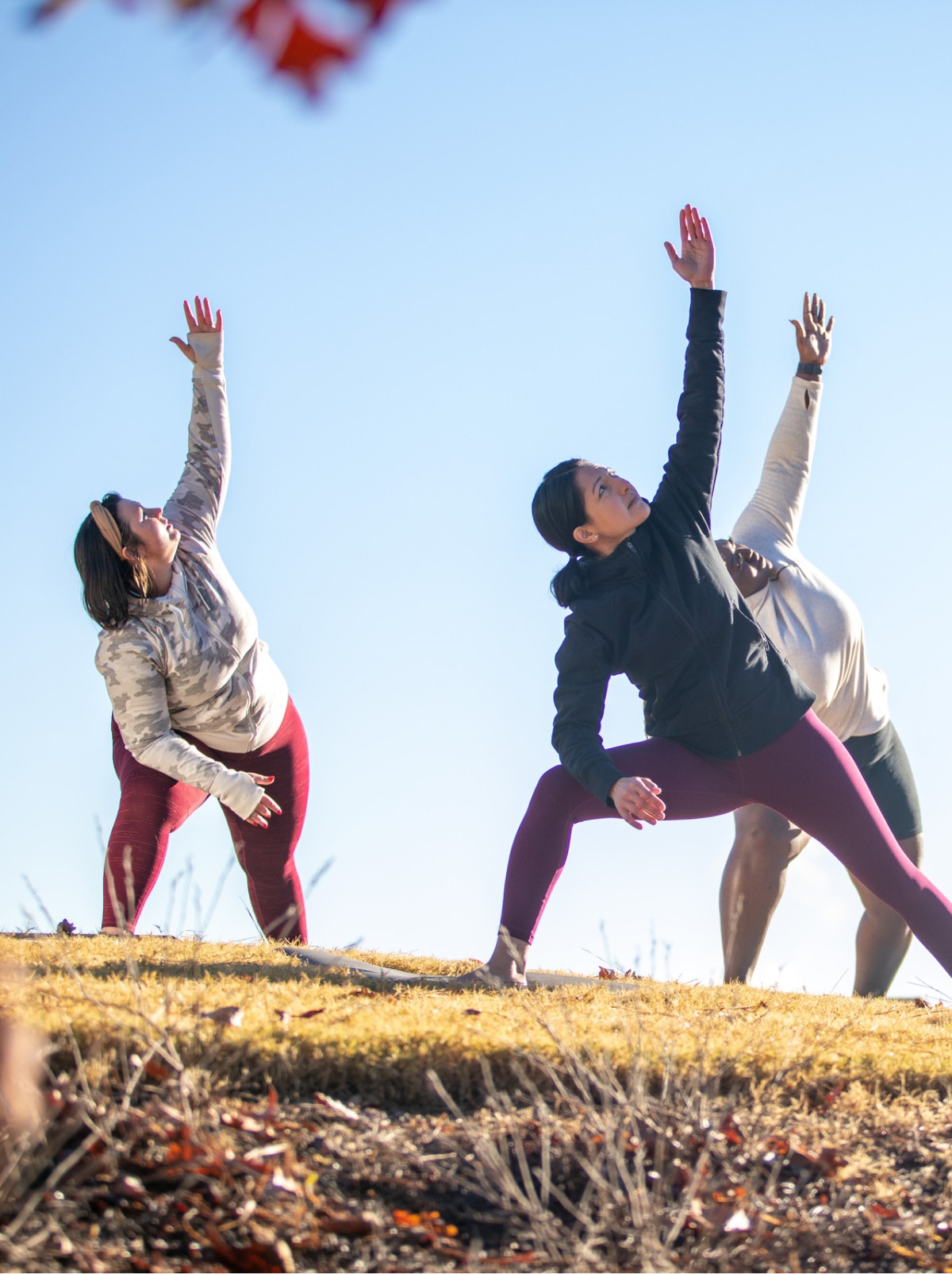 Three people doing yoga outside.