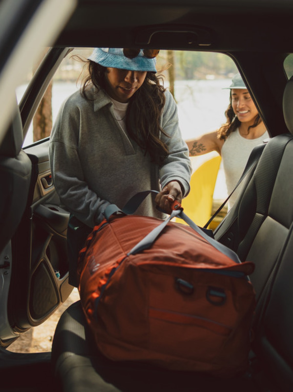 A person grabs their duffel bag from inside of a car.