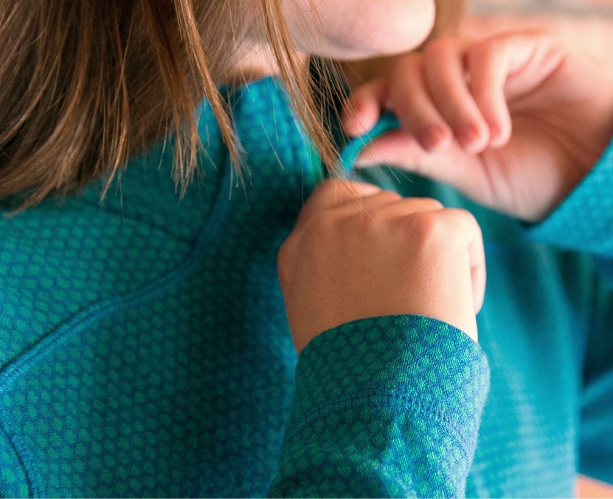 A person zips up their base layer top.