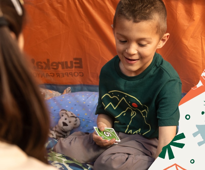 Two children play UNO inside of their tent.