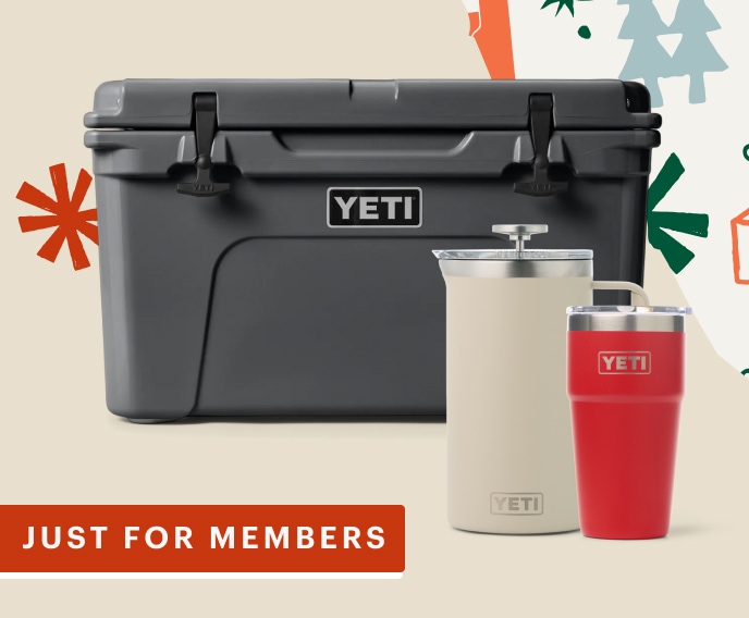 A cooler, french press, & a stackable cup from YETI on a light colored background with snowflakes.
