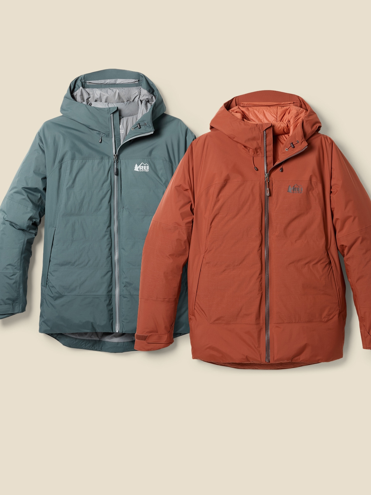 Two R E I Co-op brand jackets on a light colored background.