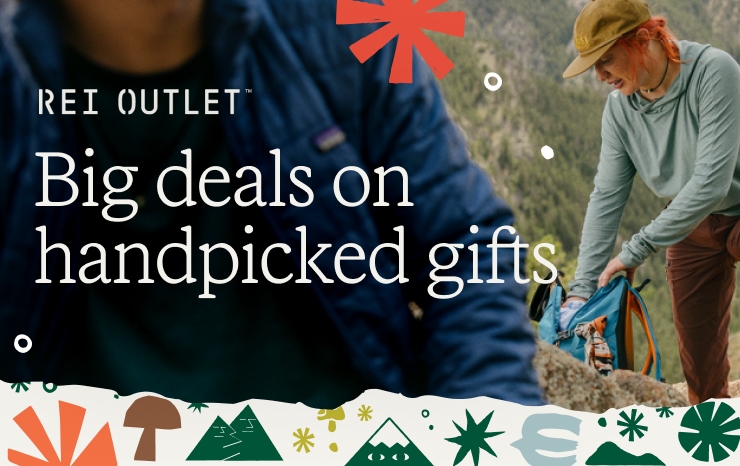 A hiker is stopped on the trail, reaching into her backpack. Headline: REI OUTLET Big deals on handpicked gifts