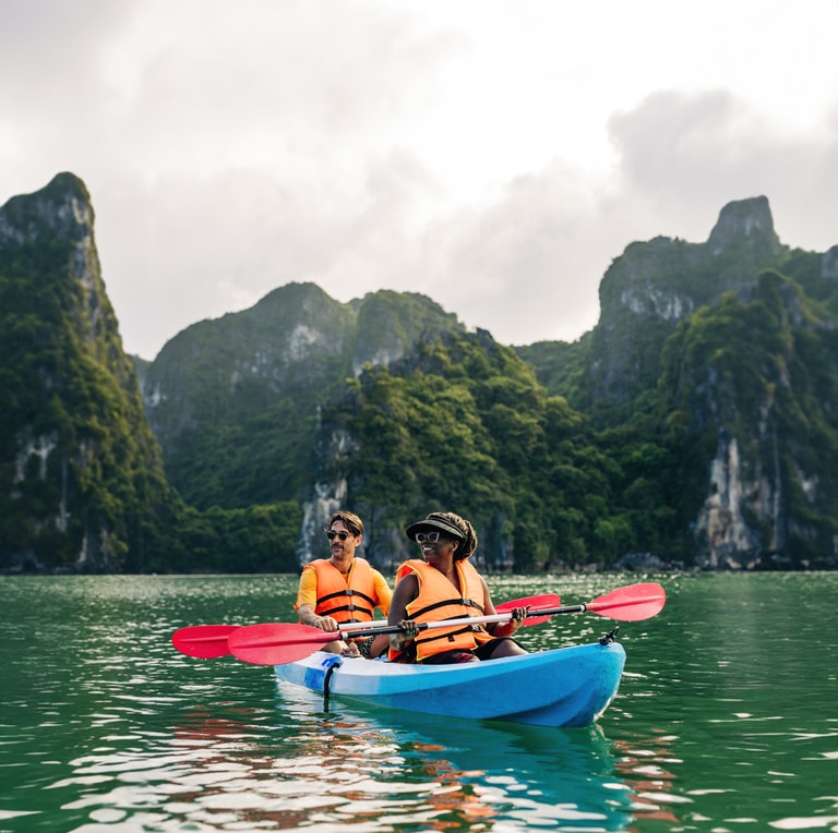 Two people paddle a kayak in Ha Long Bay on an Intrepid adventure trip