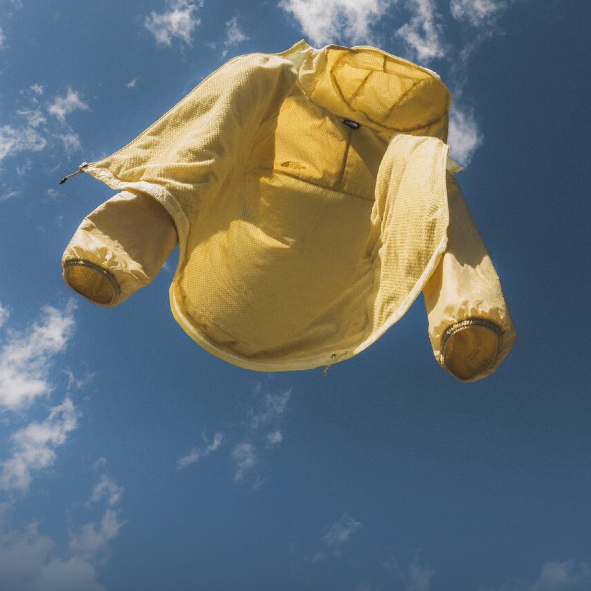 A yellow The North Face Ridgelite jacket floats off into the sky.