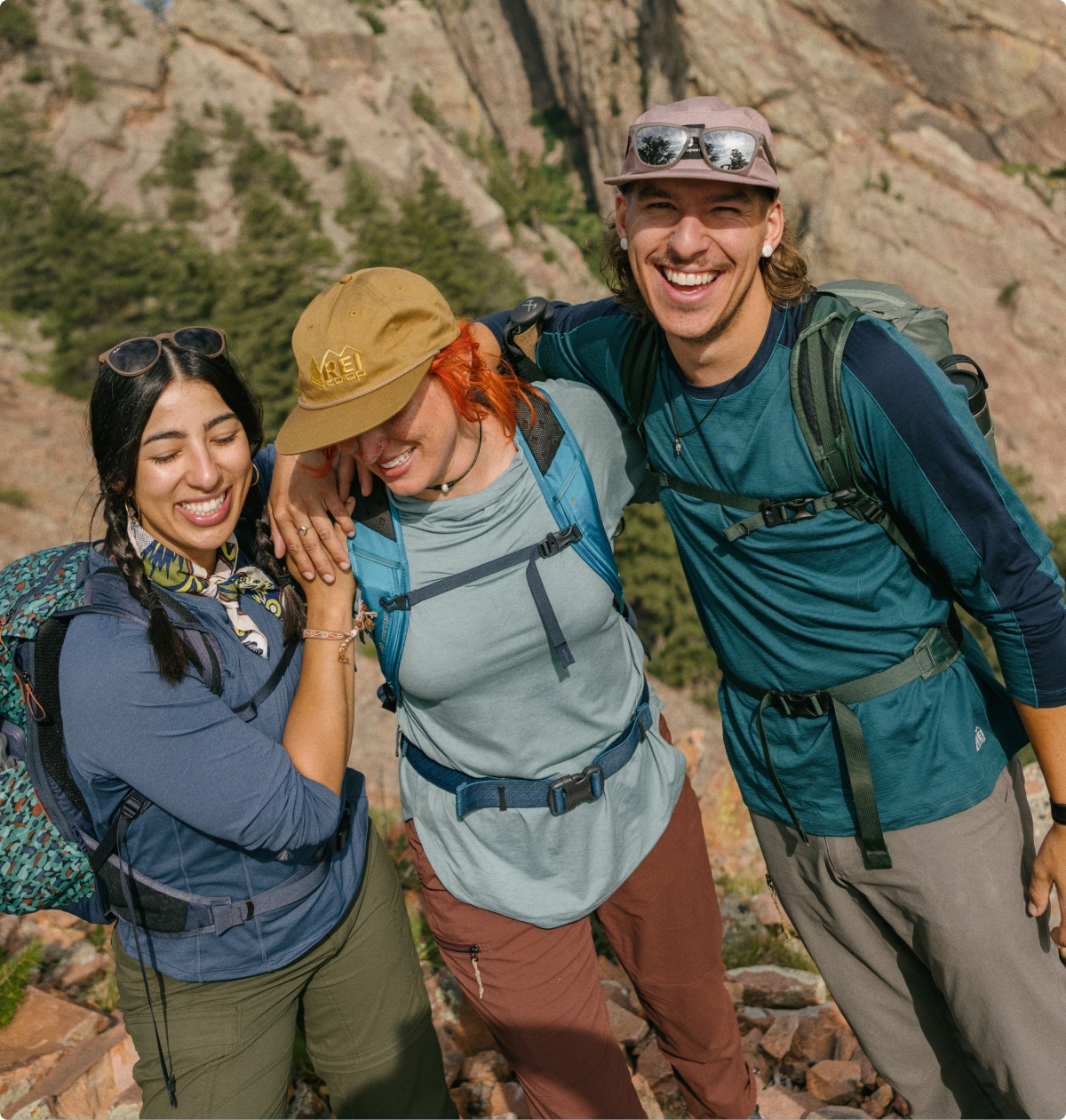Three people laugh and smile for the camera while on a hike.