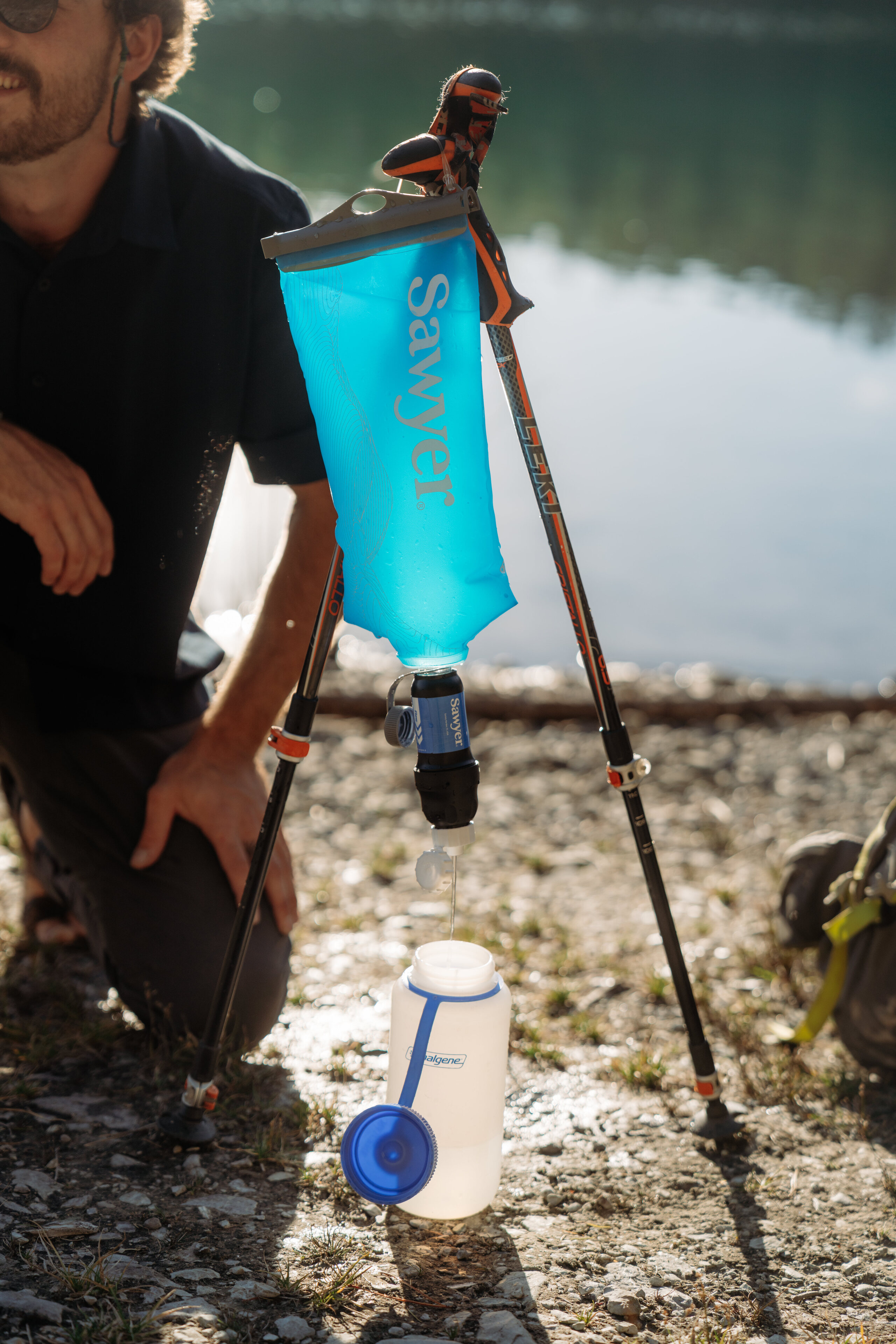 A backpacker uses a water filter to treat water 