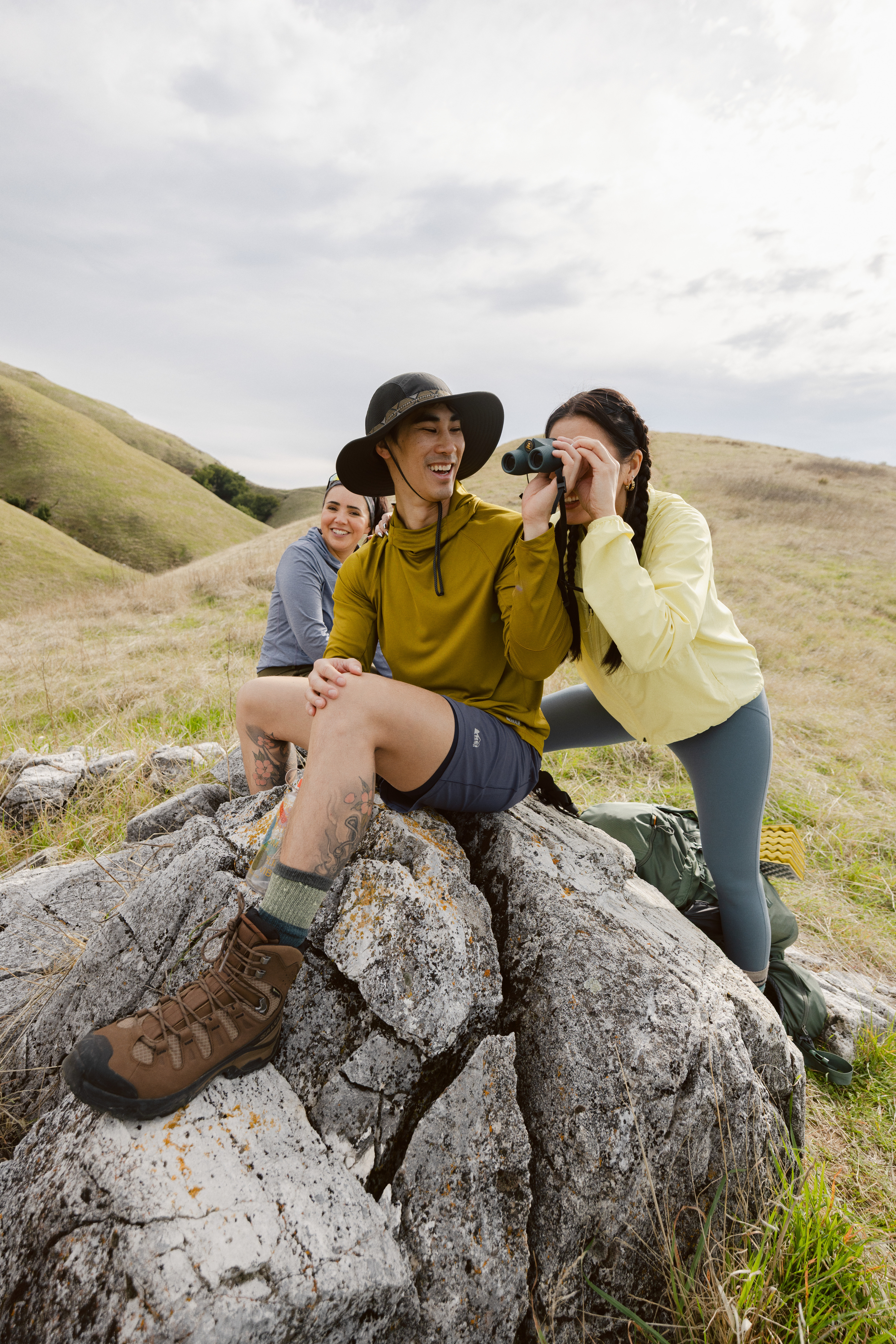 A group of people take a break from hiking to look through a pair of binoculars.