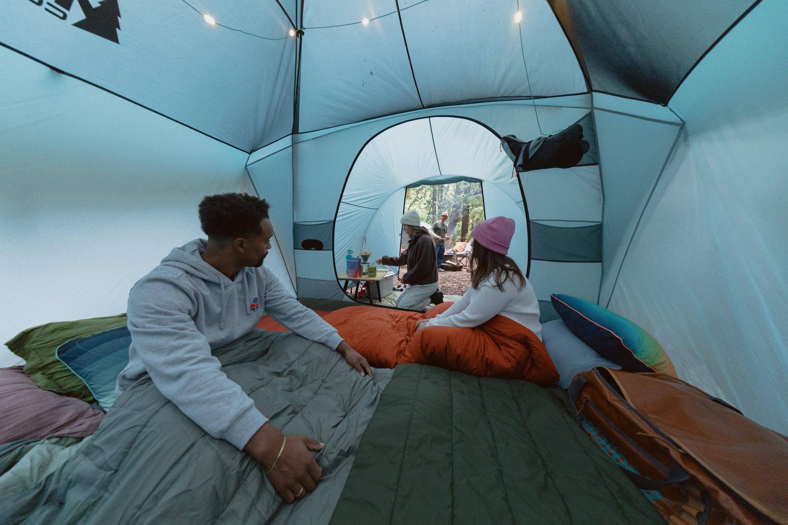 Photo of three campers in sleeping bags inside a large tent