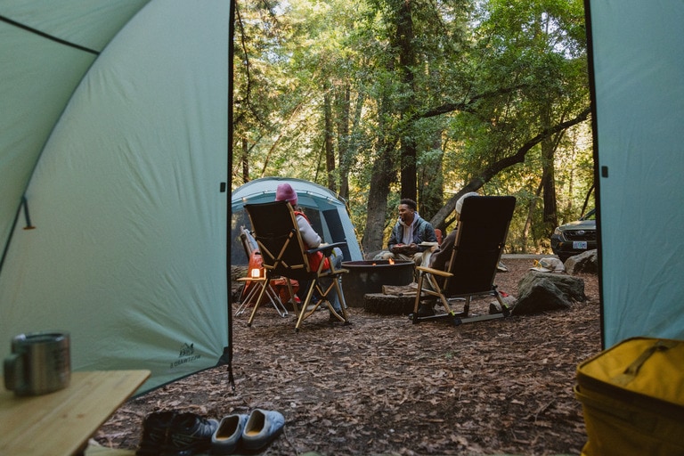 Picture of people sitting in camp chair outside their tent at a campsite