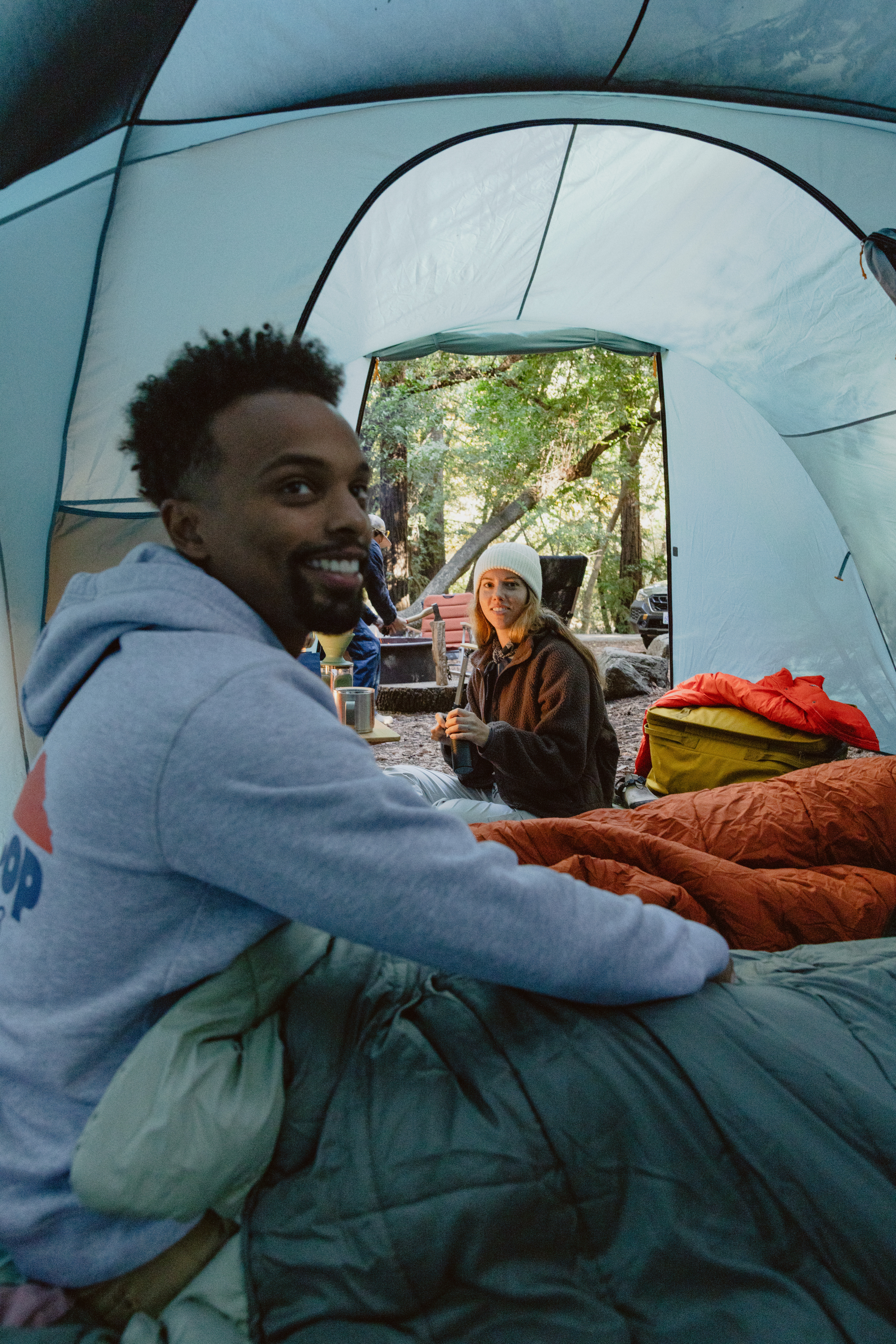 Two people smiling inside of a tent.