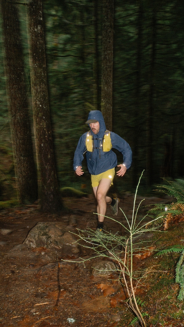 A person runs on a wooded trail at night.