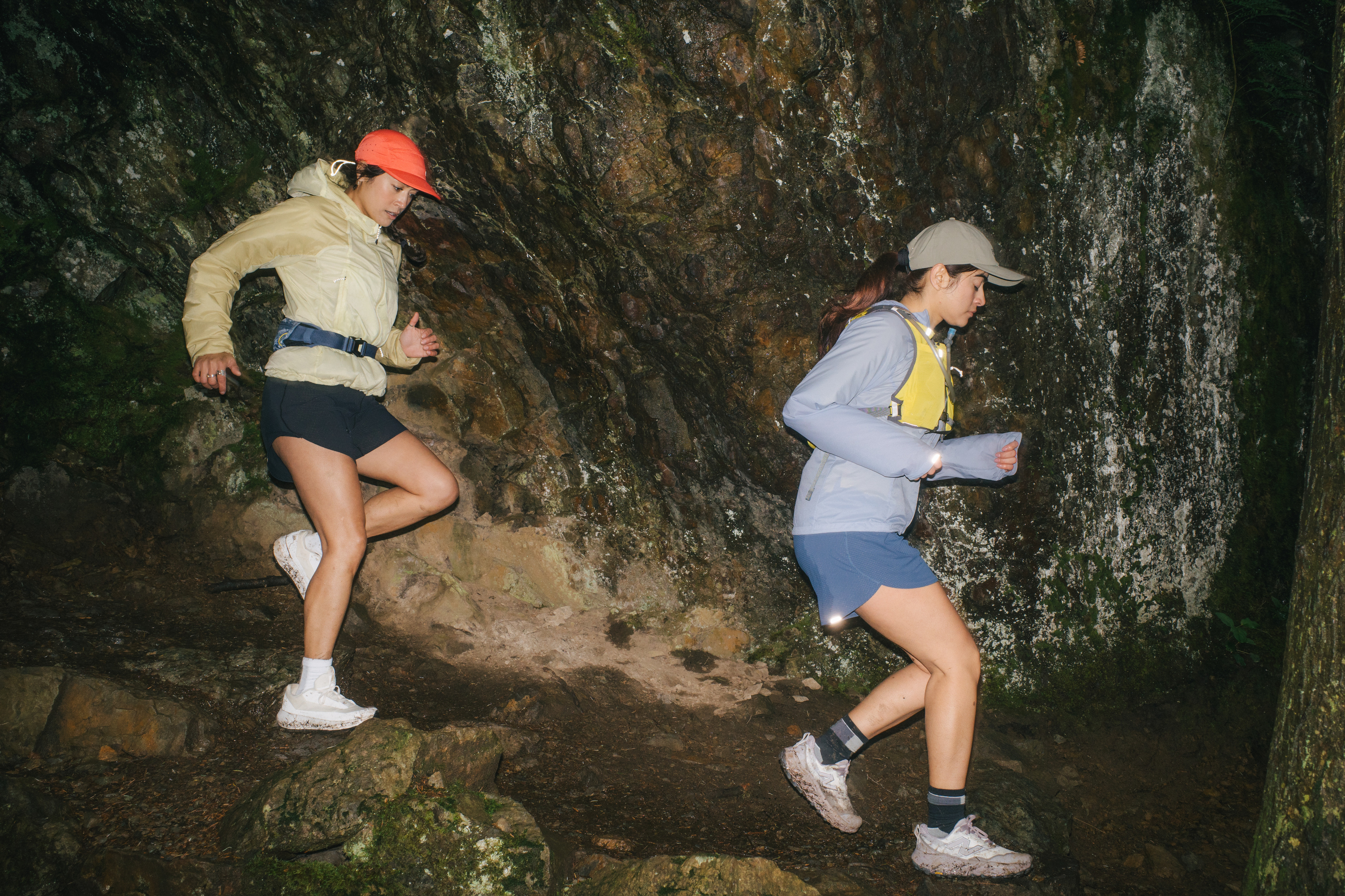 Two people run down a wet trail at night.