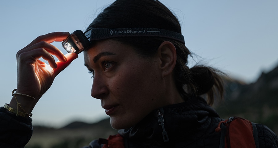 A person turns on their Black Diamond headlamp.