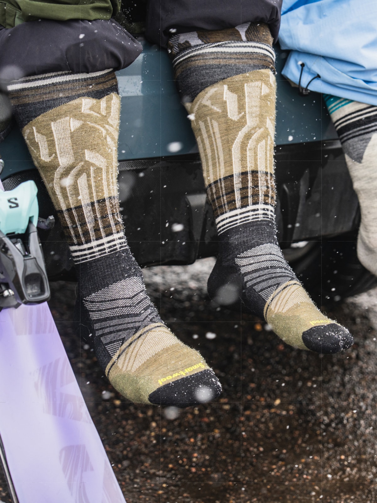 Two people wearing Smartwool socks stop to take a break after a long day of snowsports.