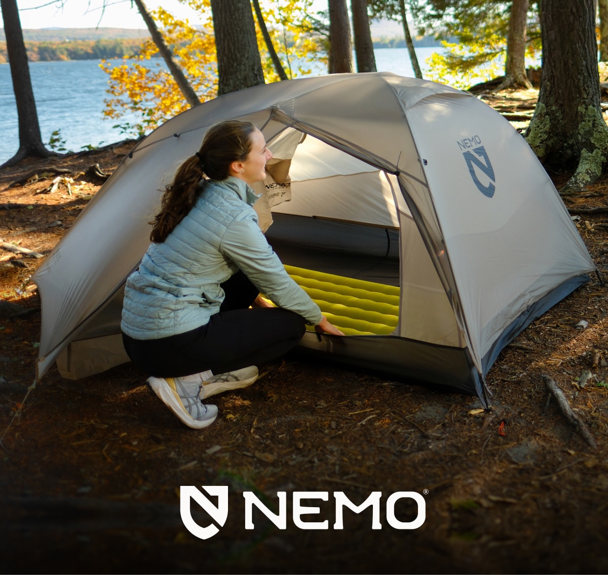A person smiles and puts their sleeping pad inside of their NEMO tent.
