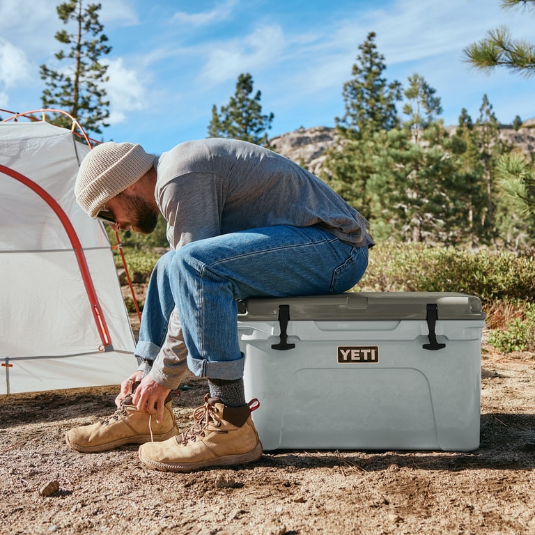 A person sits on a YETI hardsided cooler