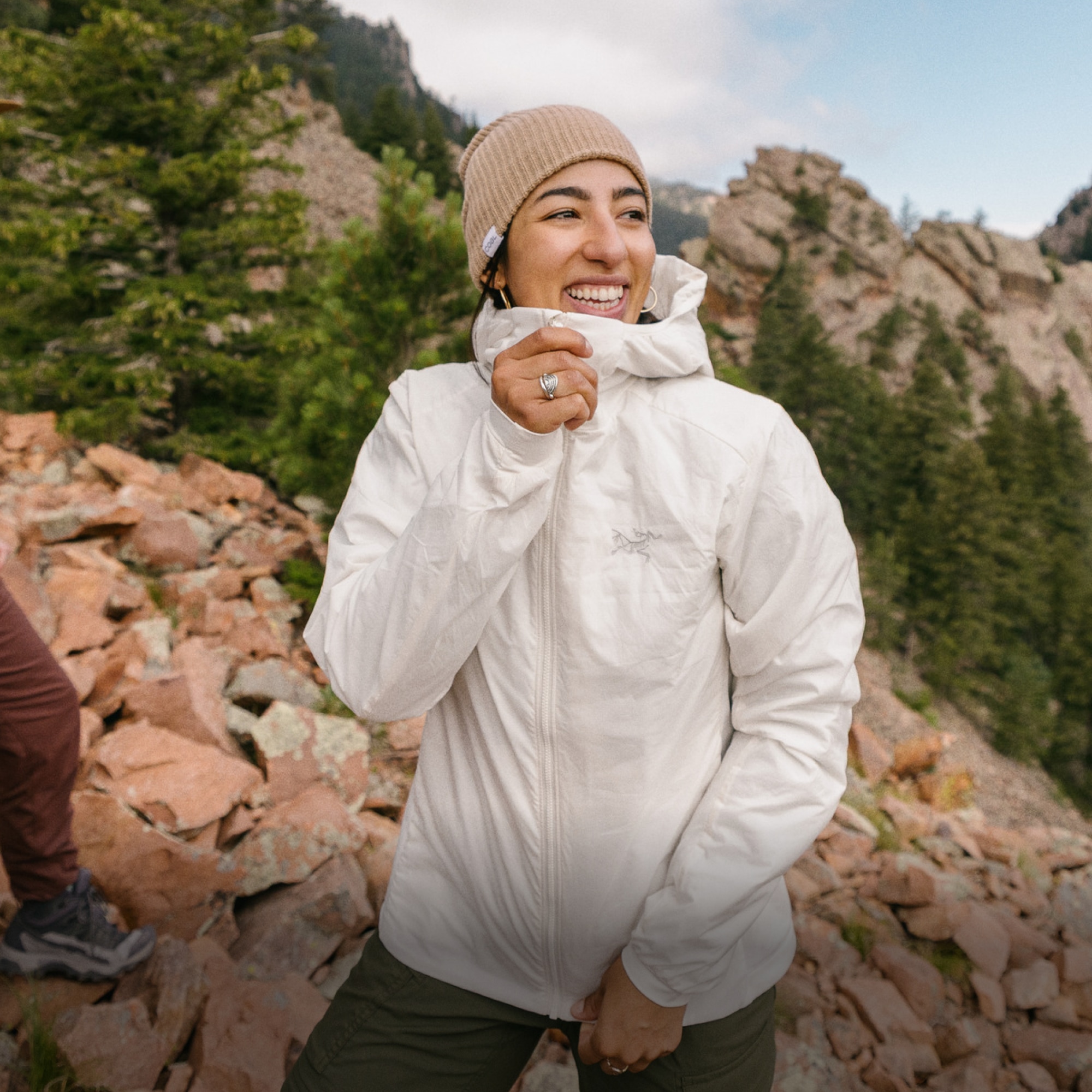 A person zips up their Arc’teryx jacket while on a hike.