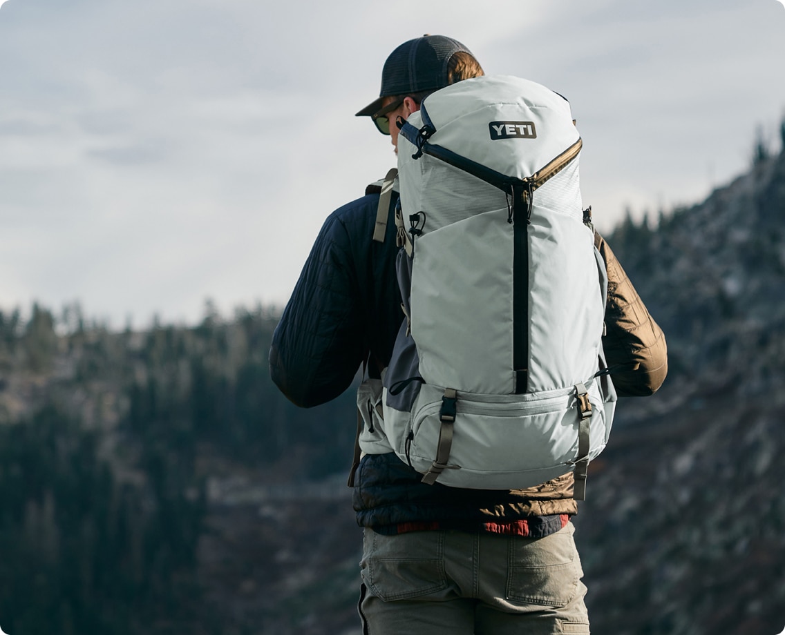 A person takes in the view while wearing their YETI backpack.