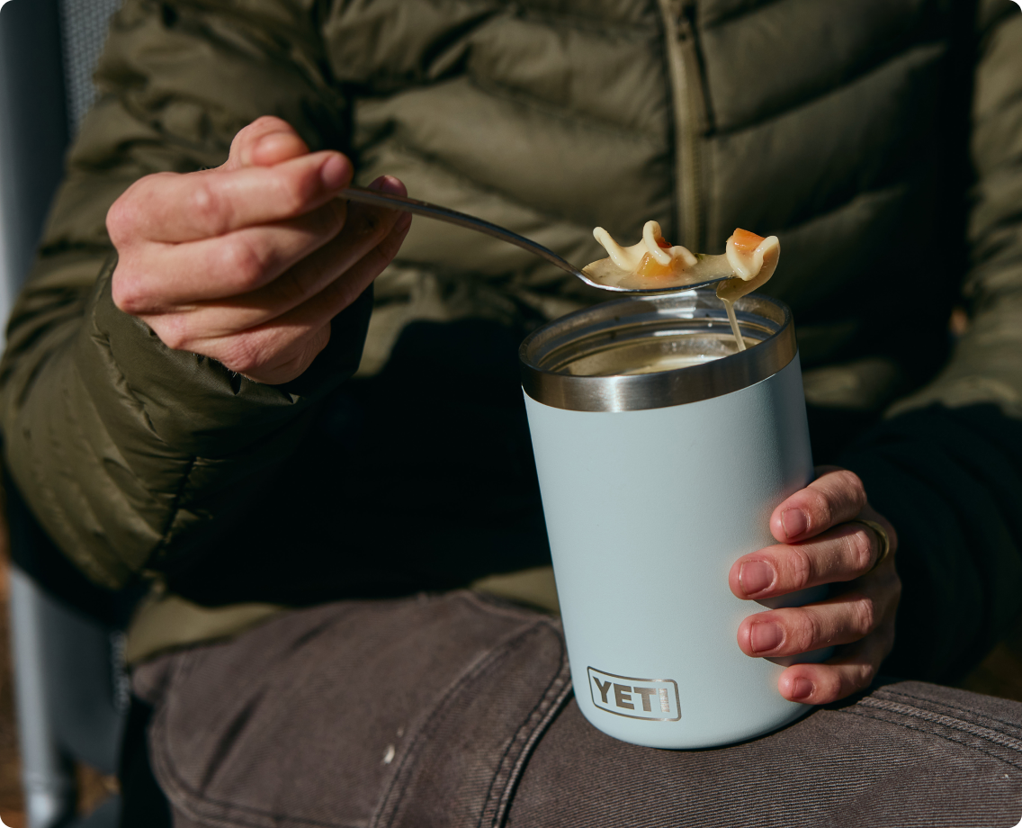 A person eats chicken noodle soup out of their YETI Food Jar.