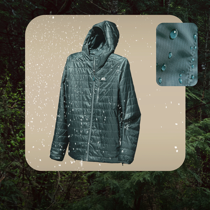 An R E I Co-op brand jacket with water beading off of it on a light colored background over an image of a dense forest.